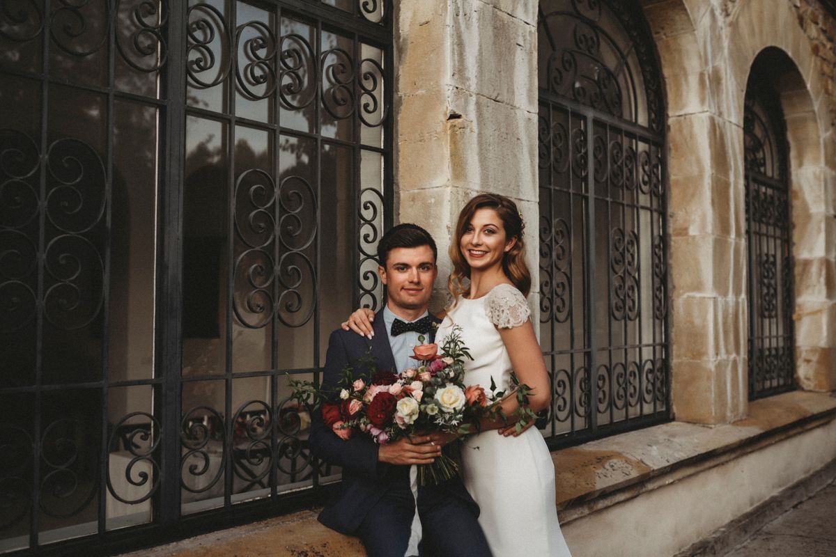 A couple in front of a stone building with large iron gates.