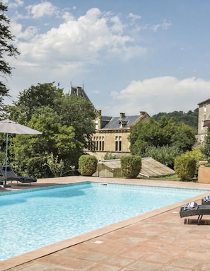 A swimming pool with lounge chairs and a building in the background.