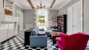 Una sala de estar con piso a cuadros, una chimenea, una estantería y vistas al exterior.