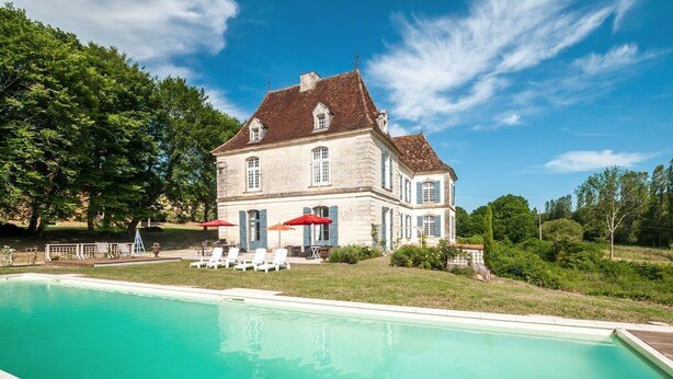 Una casa grande con piscina, mobiliario de exterior y un jardín bien cuidado.