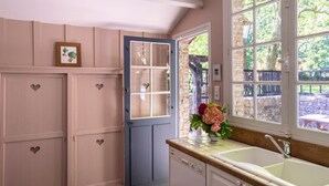 A kitchen with a large window, a sink, and cabinets with heart-shaped handles.