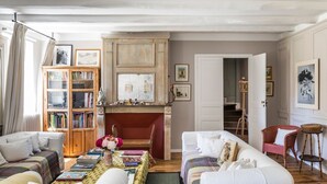 A cozy living room with a fireplace, a bookshelf, and a dining area.