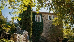 Un edificio de piedra con paredes cubiertas de hiedra y una ventana con contraventanas.
