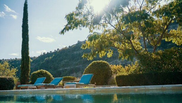 Zona de piscina con sillones de descanso y vista a un paisaje montañoso.