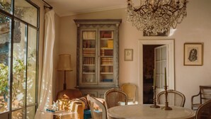 Una habitación acogedora con una mesa redonda, sillas de mimbre, una estantería y una araña.