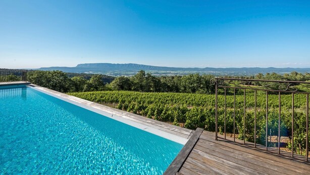 A swimming pool with a wooden deck and metal railing, surrounded by vineyard rows and a clear blue sky. - Mas Du Chateau - Six Bedroom Villa, Sleeps 14 (Trets)