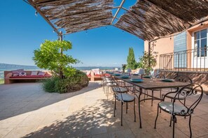 Une terrasse extérieure avec une table et des chaises, un canapé et une vue sur le paysage.