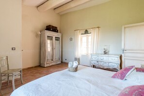 A bedroom with a large bed, a dresser, a chair, and a wardrobe.