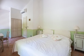 Une chambre à coucher avec un lit, deux tables de chevet avec des lampes, une chaise et une armoire.