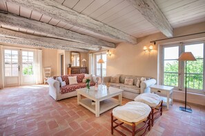 Un salon spacieux avec un plafond haut, une cheminée et une vue dégagée grâce à de grandes fenêtres.