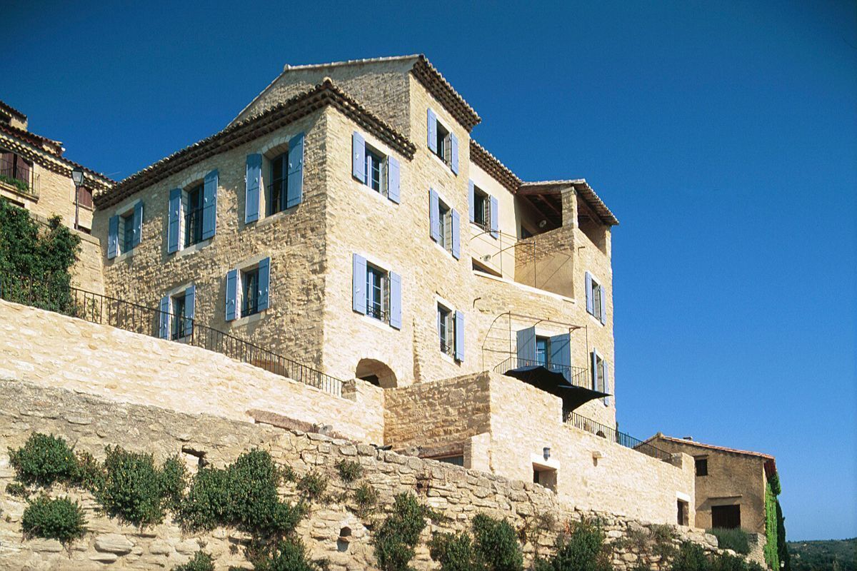 A stone building with multiple windows and balconies, situated on a hillside.