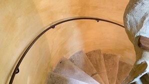 Eine Wendeltreppe mit einer beigefarbenen Wand und einem Fenster am oberen Ende.