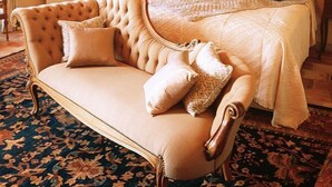 Ein Schlafzimmer mit einem großen Bett, einem Sofa, einer Kristallleuchtre und einem gemusterten Teppich.