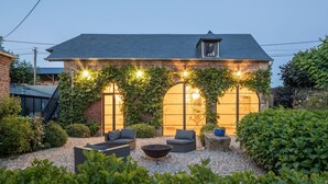 A brick house with a sloped roof, a covered patio area with outdoor furniture, and a gravel ground. - Chateau Albatre - Twelve Bedroom Castle, Sleeps 33 (Luneray)