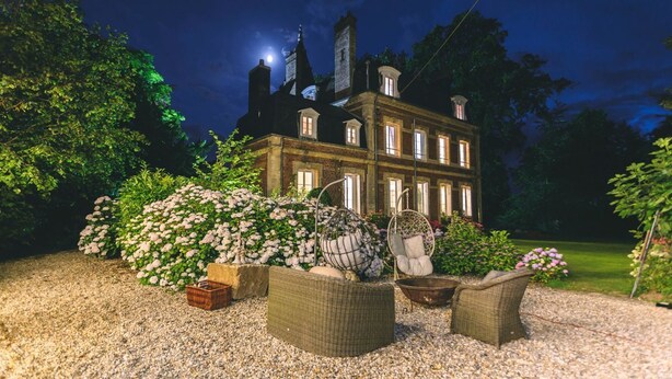 A large, historic building with multiple windows and a prominent tower, surrounded by lush greenery and outdoor seating. - Chateau Albatre - Twelve Bedroom Castle, Sleeps 33 (Luneray)