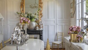 A dining room with a white table, gold chairs, a large mirror, and floral arrangements. - Chateau Albatre - Twelve Bedroom Castle, Sleeps 33 (Luneray)