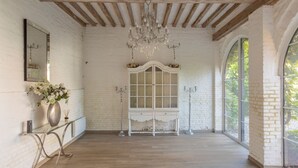 A spacious room with a wooden floor, white brick walls, a large arched window, and a white cabinet with glass doors. - Chateau Albatre - Twelve Bedroom Castle, Sleeps 33 (Luneray)