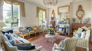 A spacious living room with a chandelier, multiple seating areas, and a large mirror. - Chateau Albatre - Twelve Bedroom Castle, Sleeps 33 (Luneray)