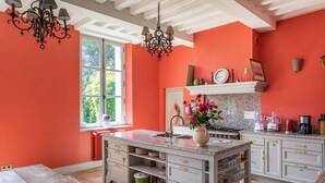 A kitchen with white cabinets, a granite countertop, and a window with a view of greenery. - Chateau Falaises - Nine Bedroom Castle, Sleeps 15 (Ingouville)