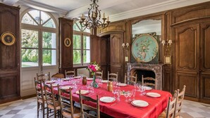 A dining room with a red tablecloth, wooden chairs, a chandelier, and a fireplace with a decorative mirror. - Chateau Falaises - Nine Bedroom Castle, Sleeps 15 (Ingouville)