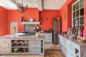 Een keuken met een groot eiland, witte kasten en een rode accentmuur.