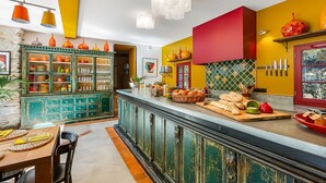 A vibrant kitchen with a central island, a green cabinet with glass doors, and a red upper cabinet.
