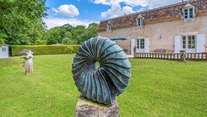 Une sculpture dans un jardin, avec un bâtiment en arrière-plan.