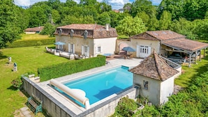 Une grande maison avec une piscine, une terrasse et un jardin.