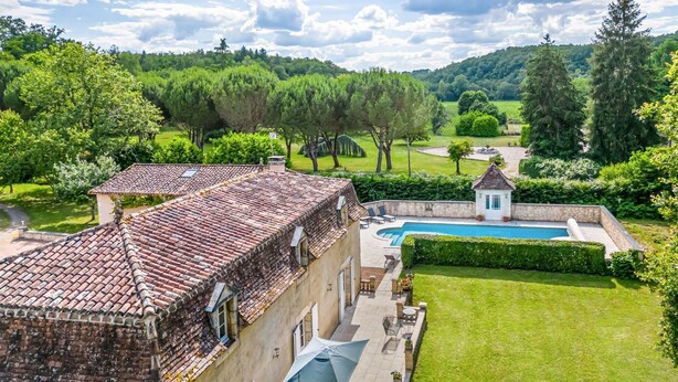 Une villa avec un toit en tuiles, une piscine et un jardin bien entretenu.