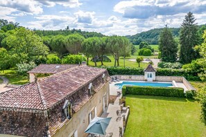 Une villa avec un toit en tuiles, une piscine et un jardin bien entretenu.