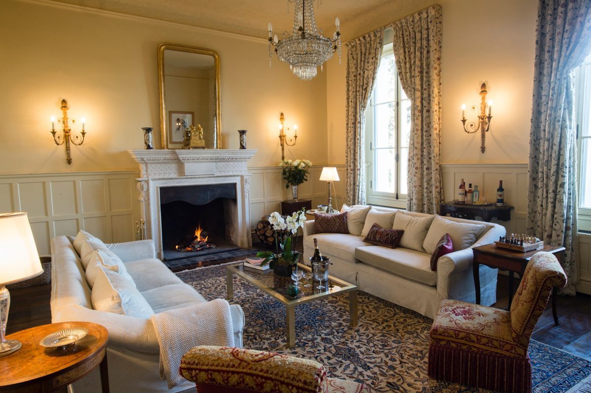 Un salon traditionnel avec une cheminée, des canapés, une table basse et un lustre.