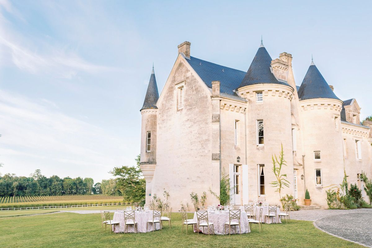 Een kasteel met meerdere torens en een binnenplaats met tafels en stoelen.