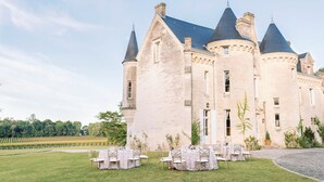 Een groot, historisch gebouw met meerdere torens en een binnenplaats met tafels en stoelen, ingericht voor een evenement.