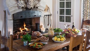 Een eettafel, gedekt met diverse gerechten, en een open haard met vuur.