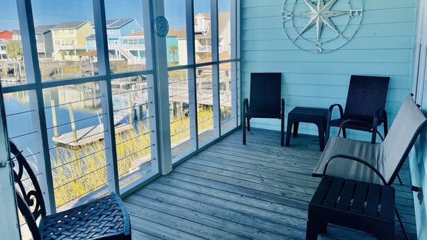 A sunlit room with large windows, a compass wall decoration, and two chairs. - Waterfront Canal Home - Private Boat Dock, Elevator & Short Walk to Beach Access (Holden Beach)