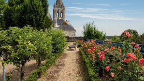 Un sendero de jardín que conduce a una iglesia con un campanario, rodeado de exuberante follaje y plantas en flor.