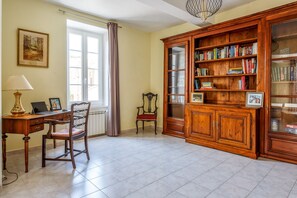 A room with a desk, chair, bookshelf, and a window with curtains.