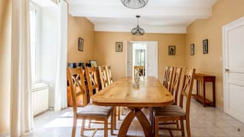 Comedor con una gran mesa de madera, varias sillas y una araña.