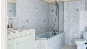 Een badkamer met bad, toilet en wastafel.