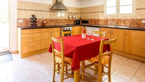 Een keuken met een eettafel voor vier personen, een fornuis en een magnetron.