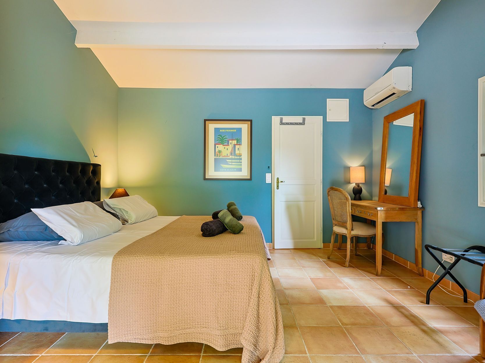 Ein Schlafzimmer mit Bett, Schreibtisch, Stuhl, Klimaanlage und einer Tür.