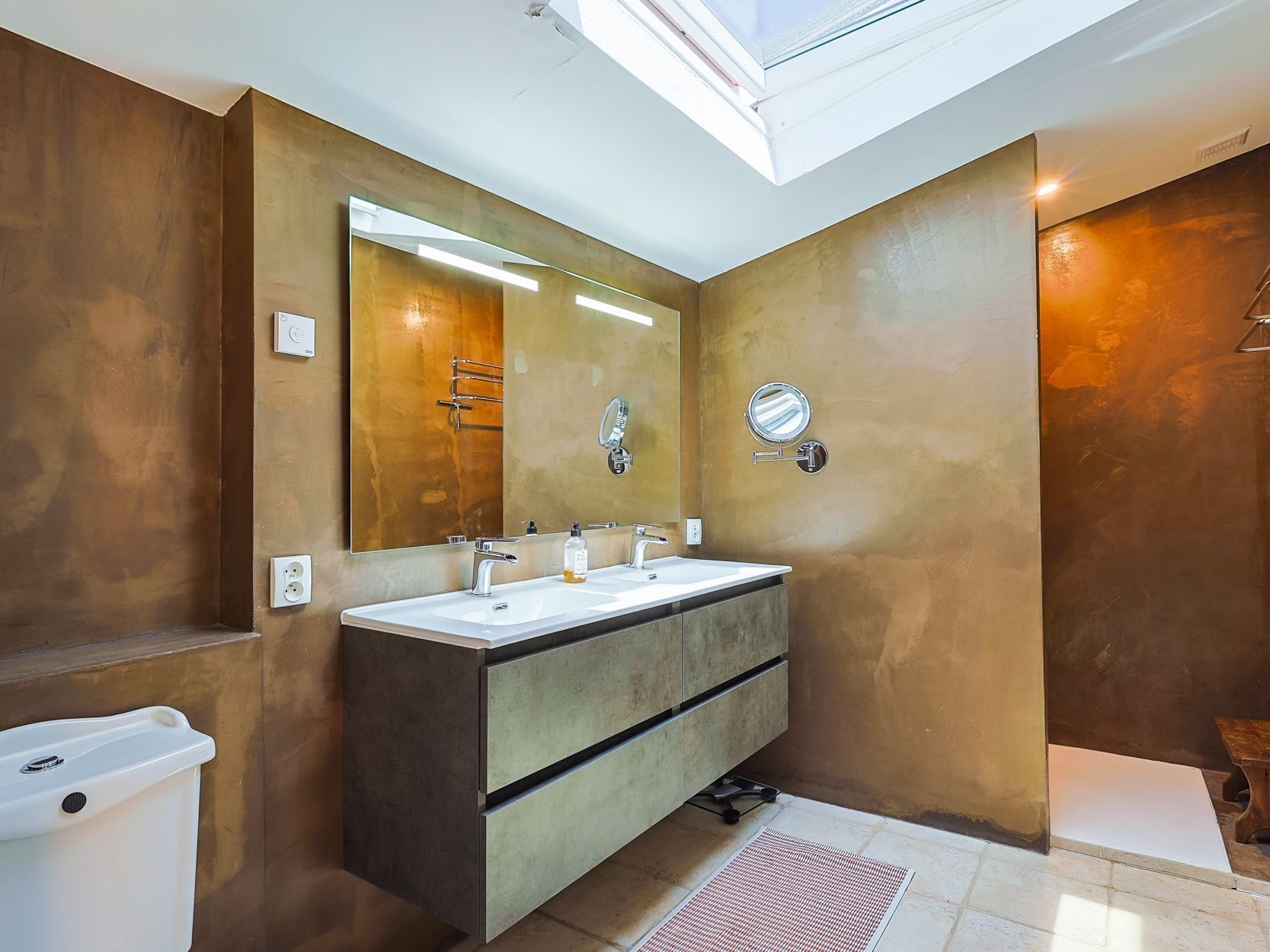 A modern bathroom with a large mirror, two sinks, and a vanity.
