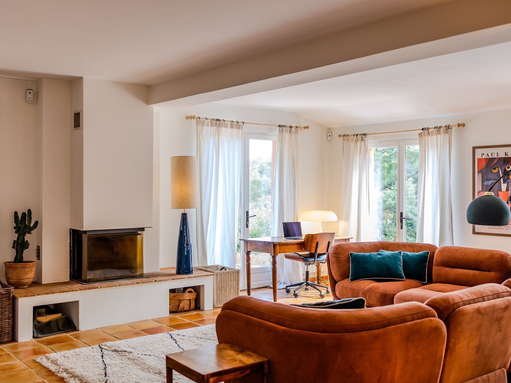 A living room with a fireplace, a sofa, a table, and a lamp.