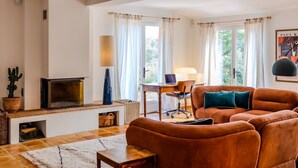 Una sala de estar con chimenea, un sofá, una mesa y una lámpara.