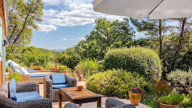 Un patio al aire libre con muebles de mimbre, una mesa y un paraguas grande.