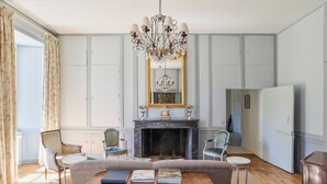 Un salon avec une cheminée, un lustre et un canapé.