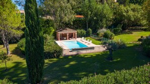 A private garden with a swimming pool, a gazebo, and a well-maintained lawn.