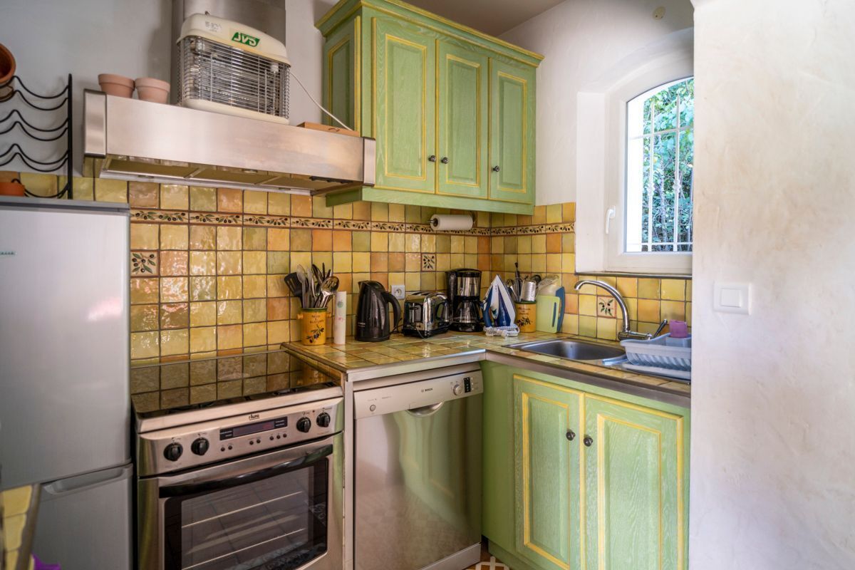 A compact kitchen with green cabinets, a built-in oven, and a dishwasher.