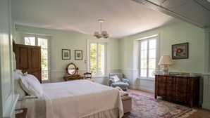A bedroom with a large bed, a dresser, a chair, and a rug.