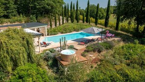Ein Schwimmbad mit Liegestühlen, einem Whirlpool und einer Pergola.